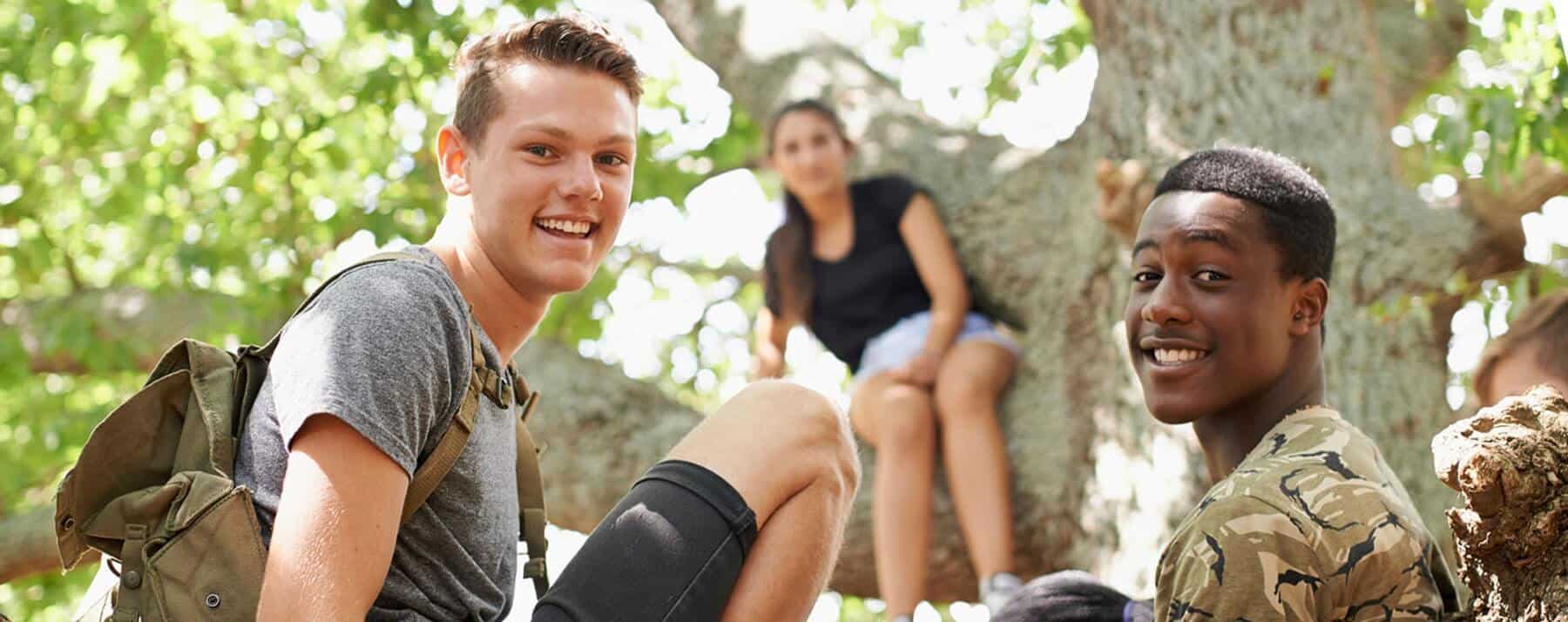 Three adolescents in recovery from drugs and alcohol sitting in a tree and hanging out together