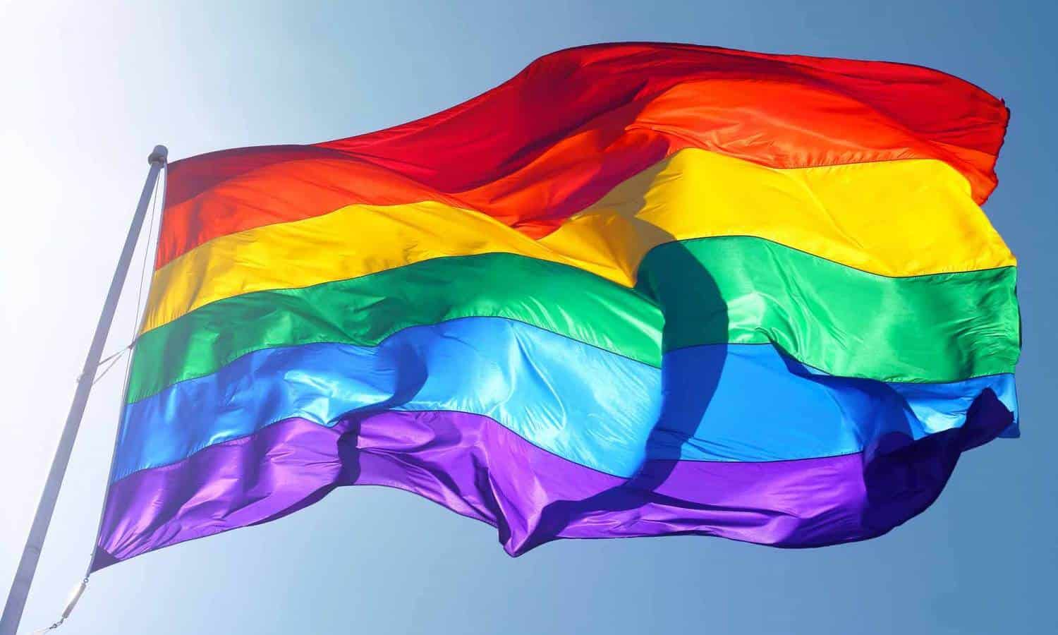 LGBTQ Rainbow Flag flying under blue skies.