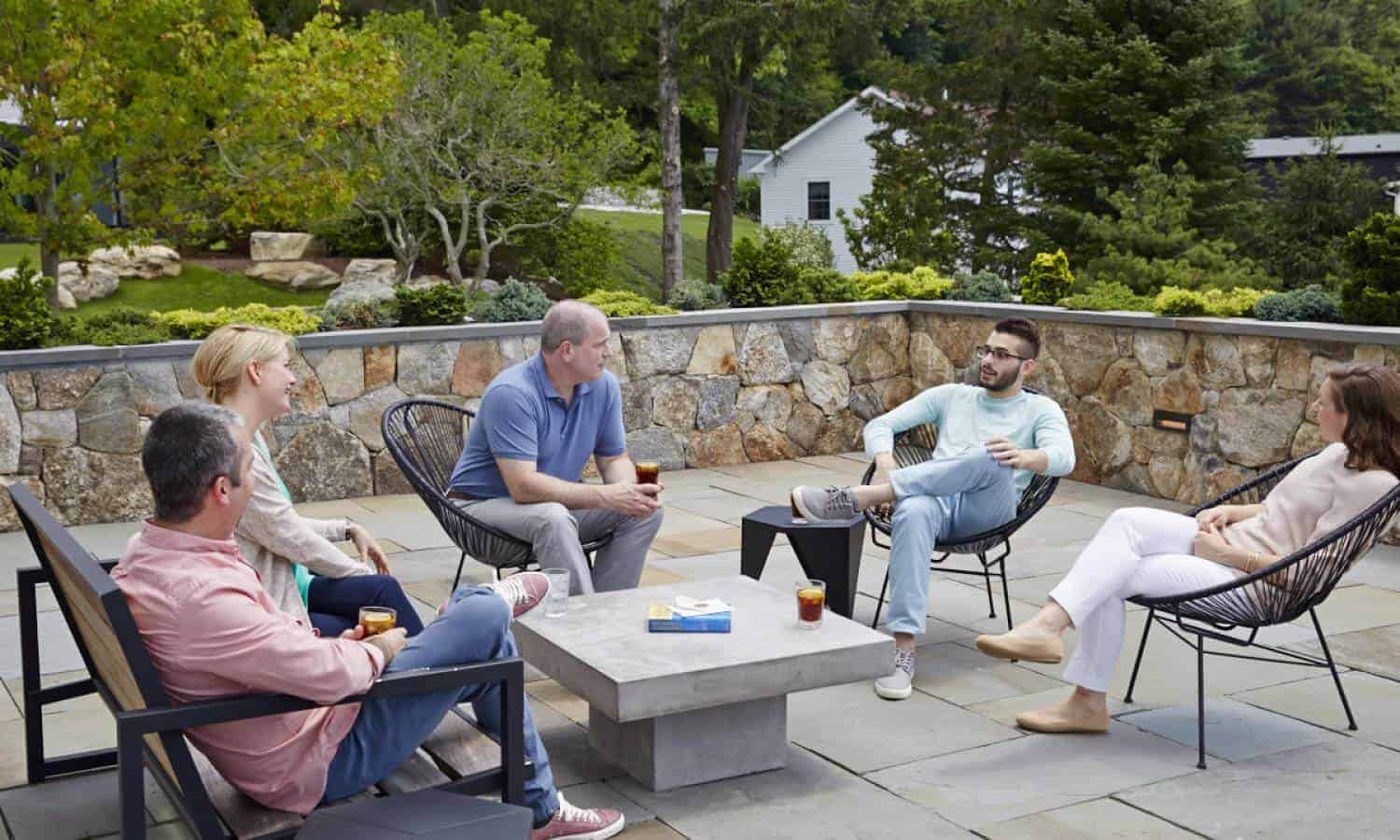 Group therapy of Men and women sitting in circle around table outside alumni center in Mountainside Canaan