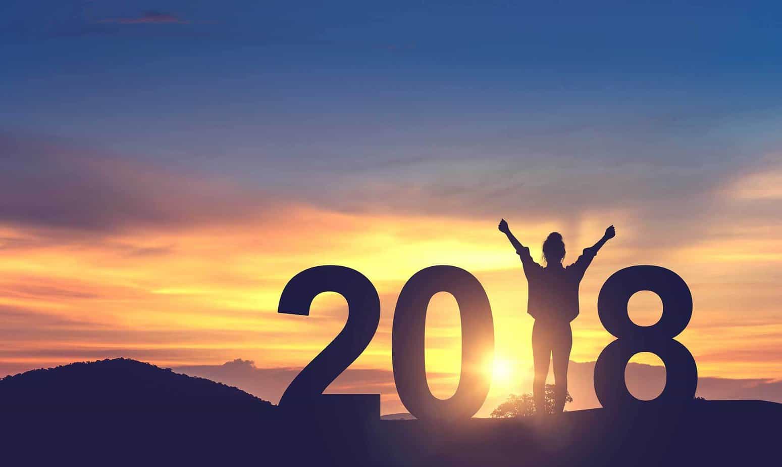 woman raising her arms celebrating the new year up in sunset for 2018