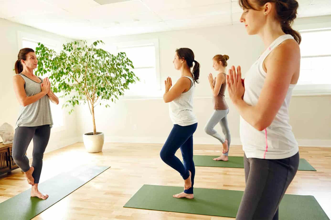Three women on mats performing tree pose in yoga class in the wellness studio at Mountainside treatment center