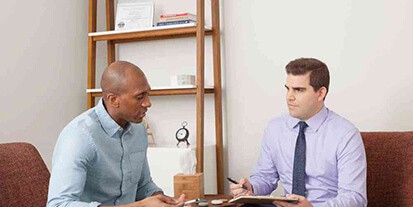 Male rehab patient in a meeting with drug addiction counselor at Mountainside treatment center.