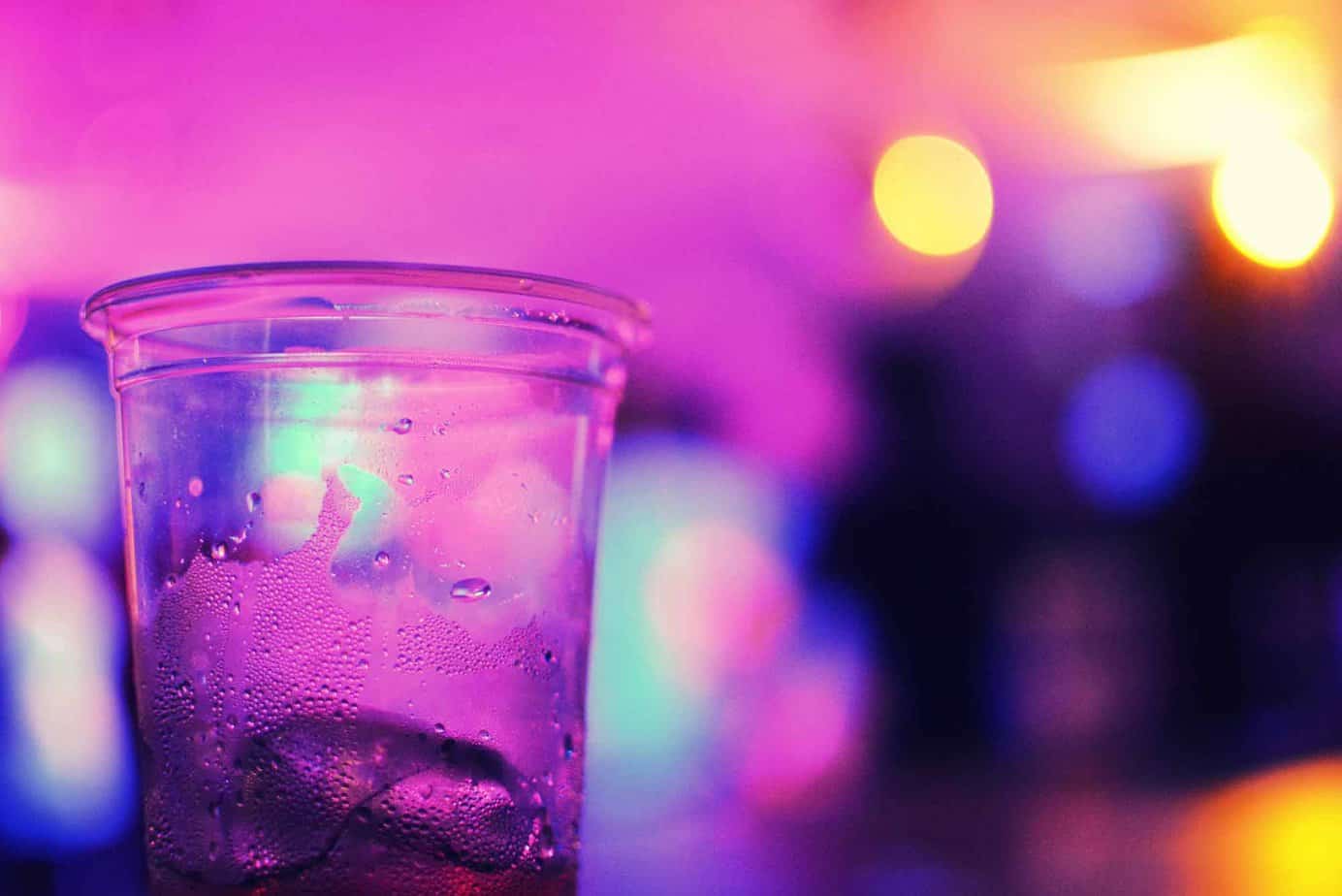 empty plastic cup with ice and condensation in purple lit room