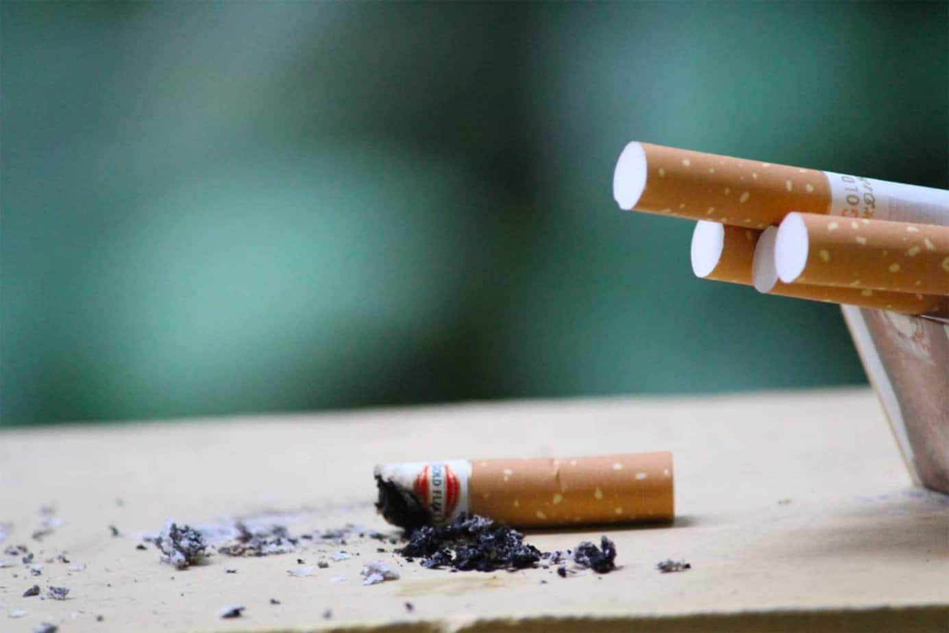 closeup of cigarettes and cigarette butt with ash