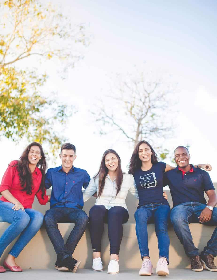 group of young adults smiling arm in arm outside