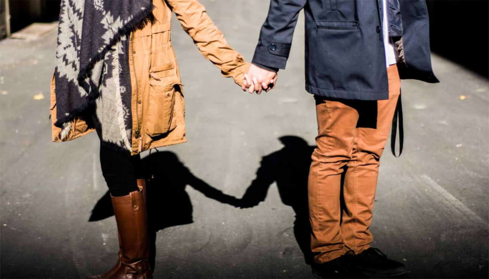man and woman in brown and blue outfits holding hands on cold day