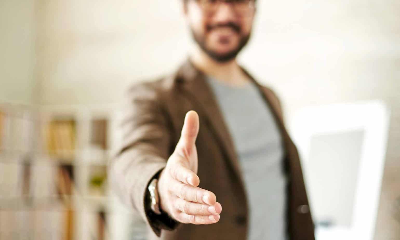 professional man in brown suit jacket extending hand for a handshake