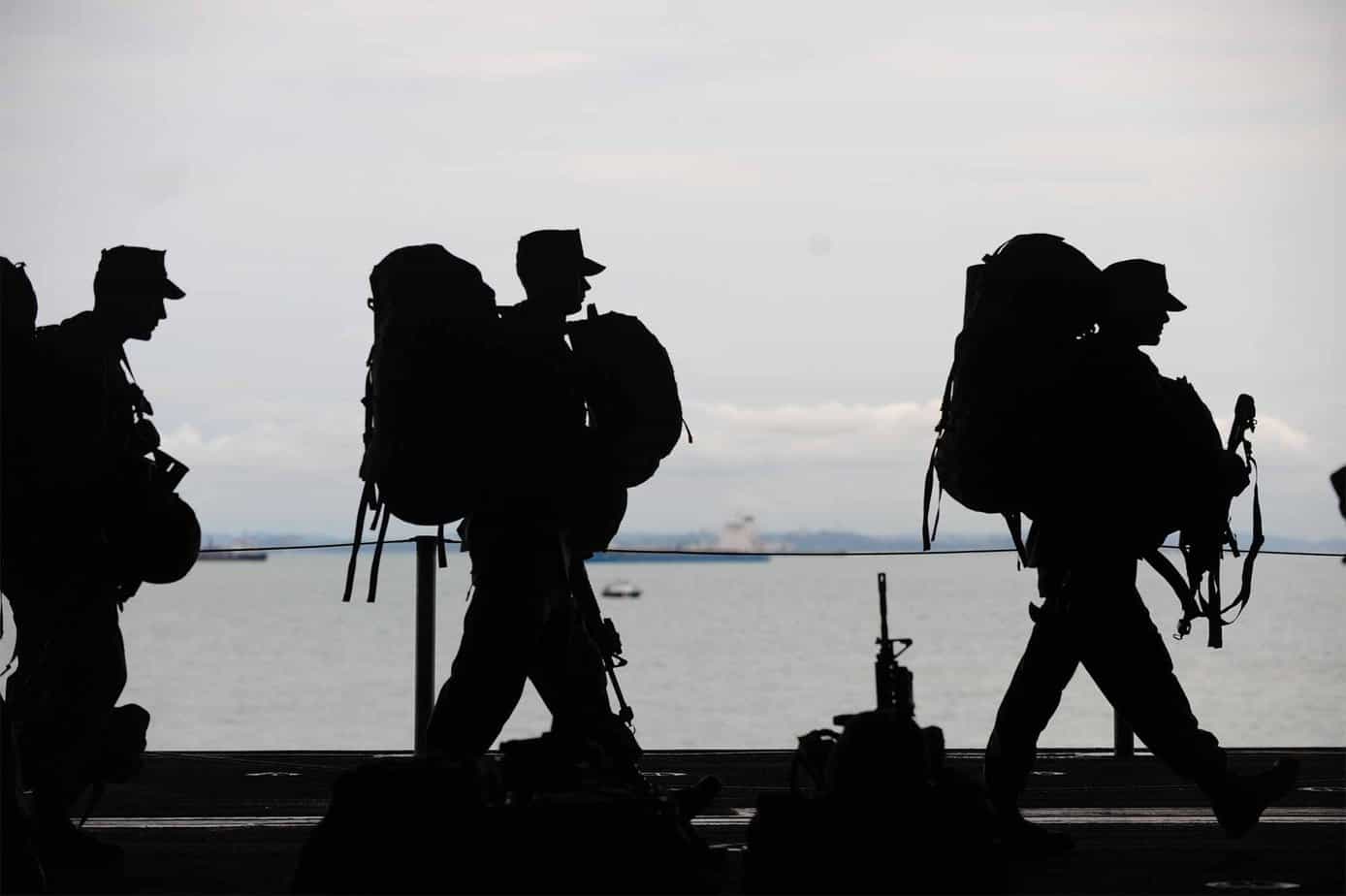 silhouette of military soldiers standing next to large body of water