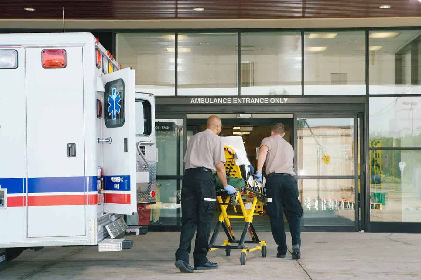patient being wheeled into hospital on stretcher steered by paramedics