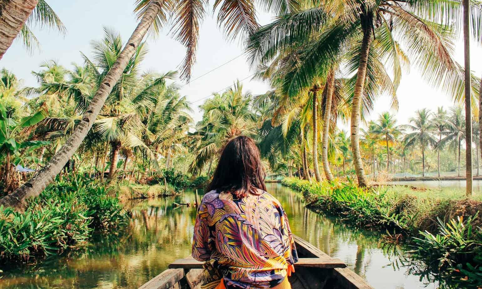 woman sitting on boat in middle of river with palm trees