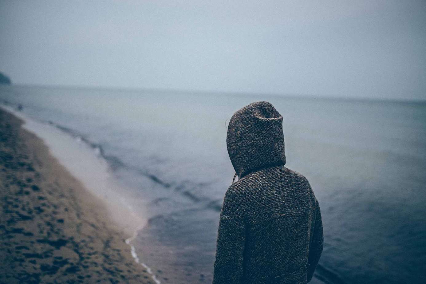 person struggling with depression walking along the beach