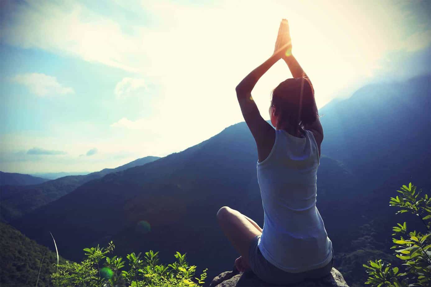 woman holding a yoga pose on top of a mountain