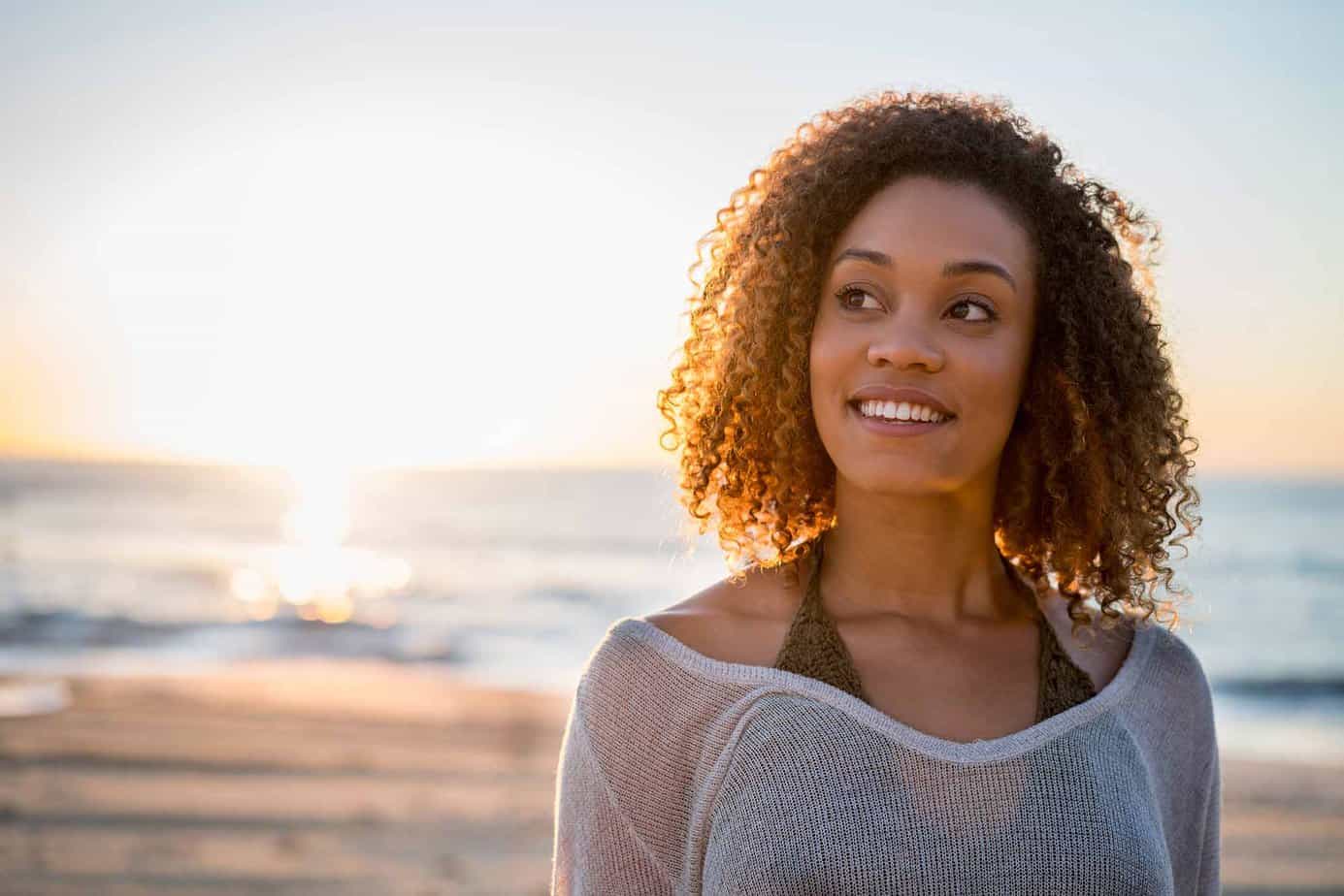 woman smiling on the beach with sunset in the background