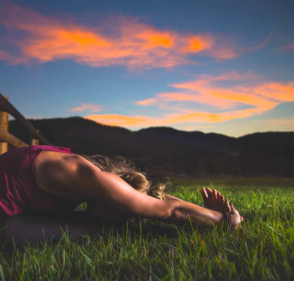 woman lying in empty field as the sun sets