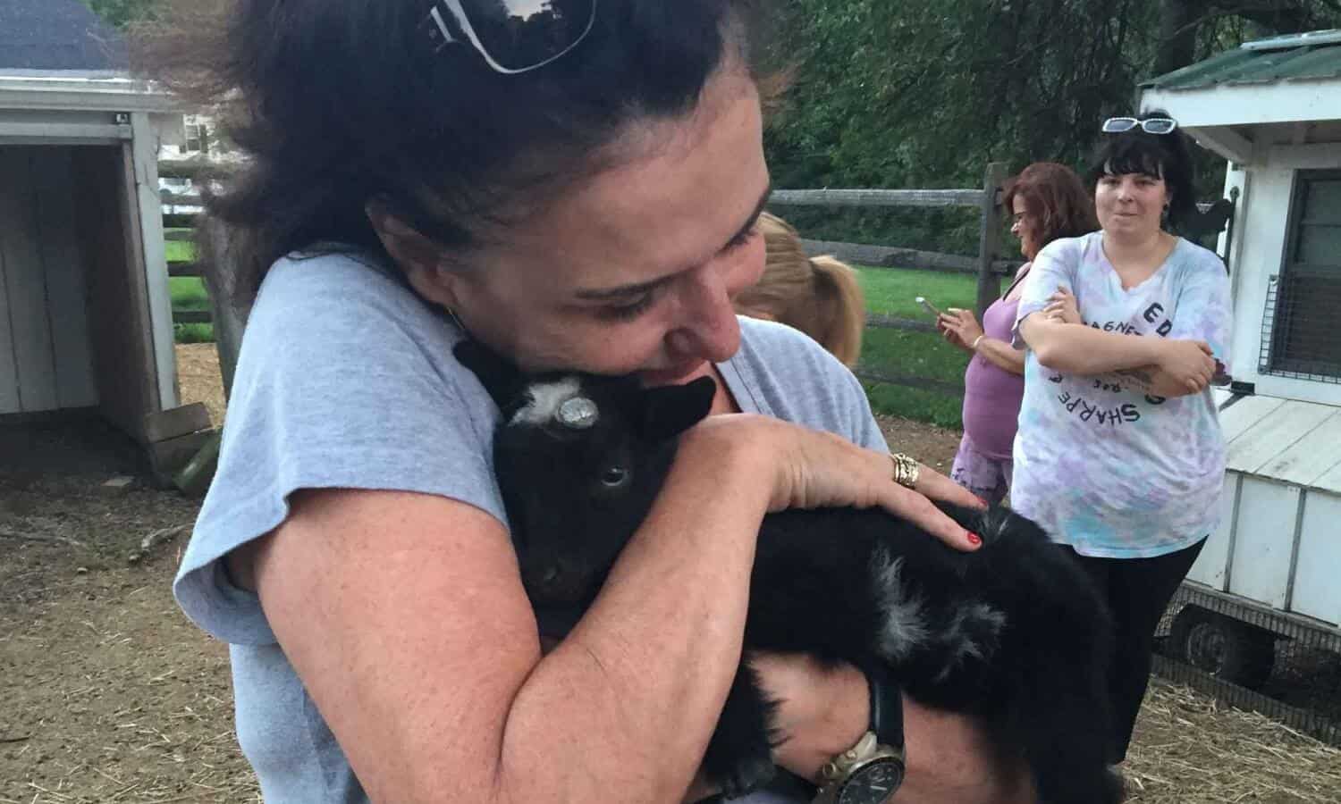 Woman holding Baby goat kid at Mountainside Treatment Center Alumni Goat Yoga Therapy in Canaan