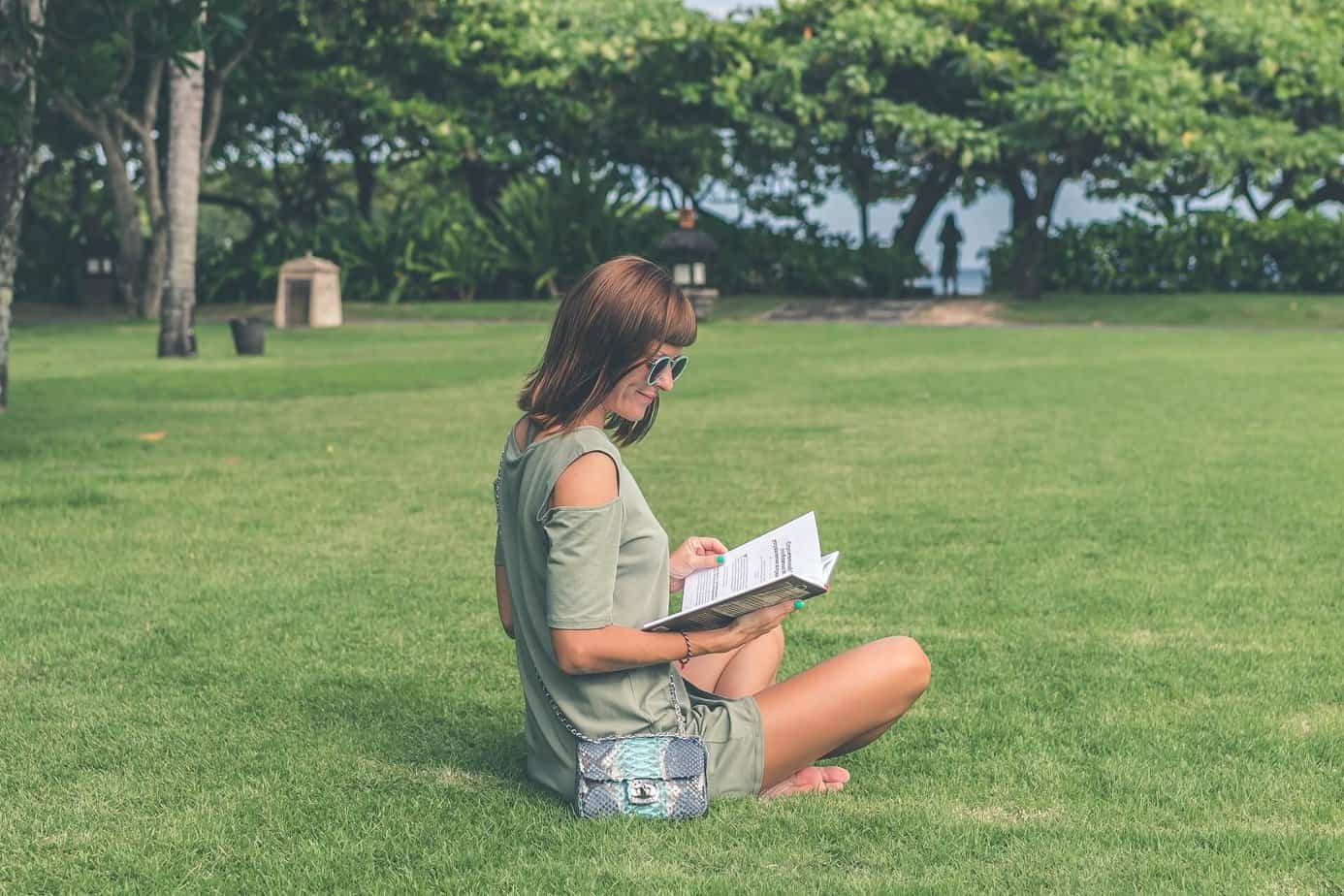 woman sitting on grass reading book
