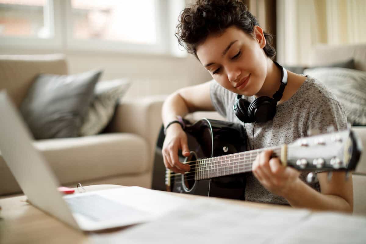 woman playing guitar in living room seated at coffee table
