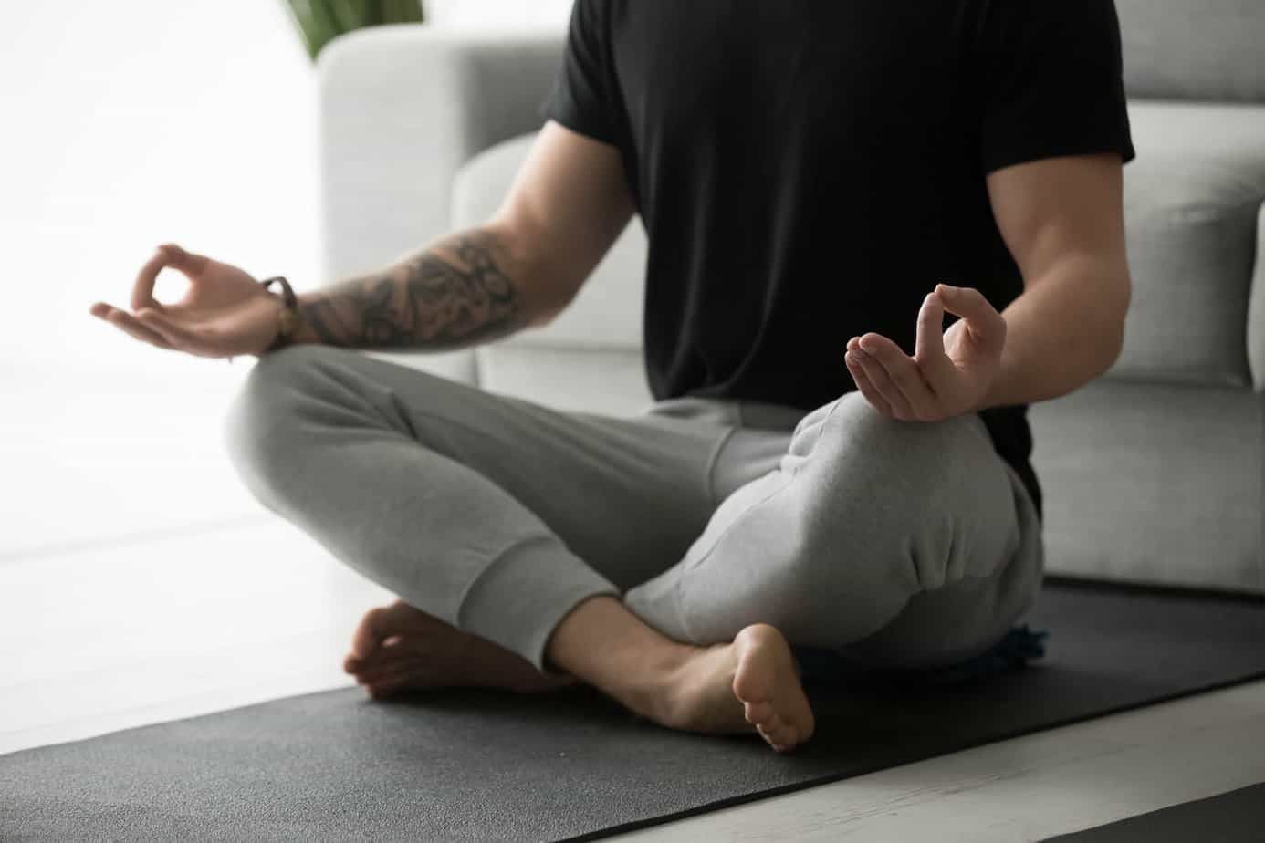 man seated on yoga man practicing meditation in athletic clothing