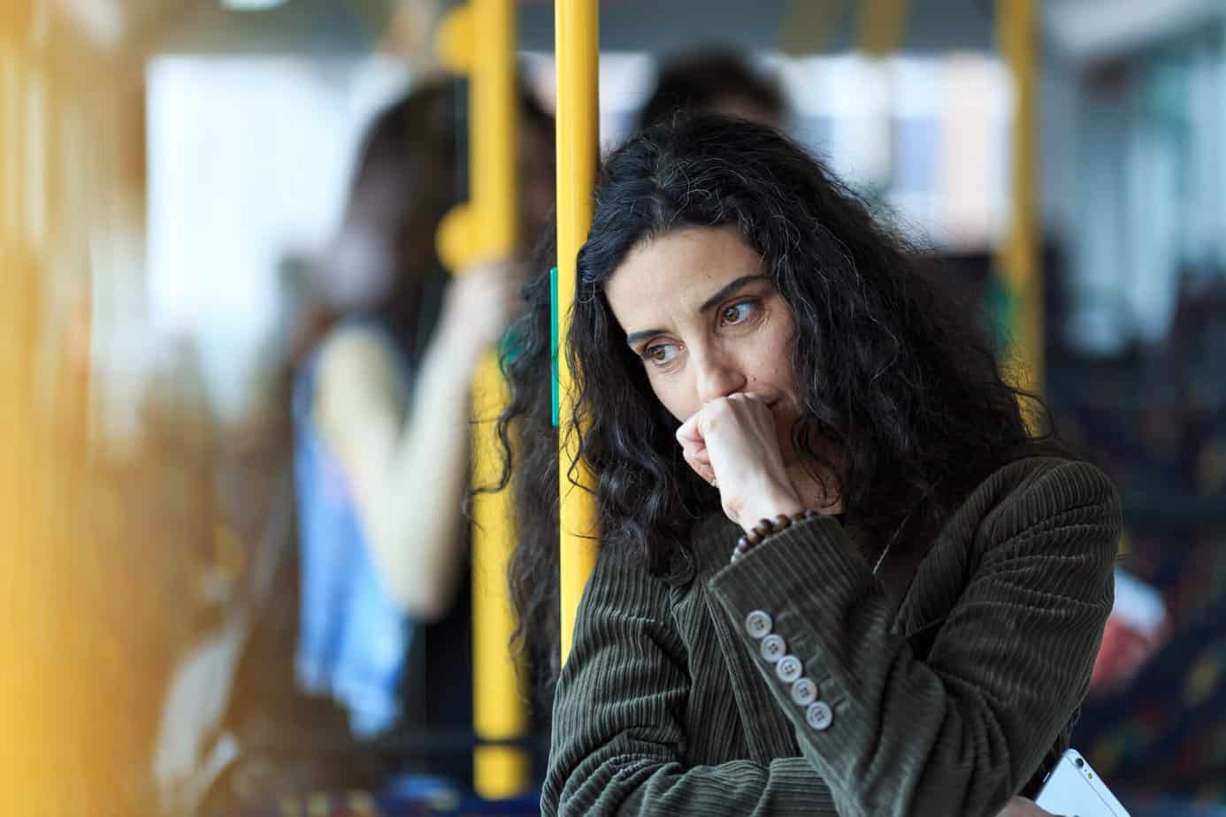 woman standing pensively on public transport bus
