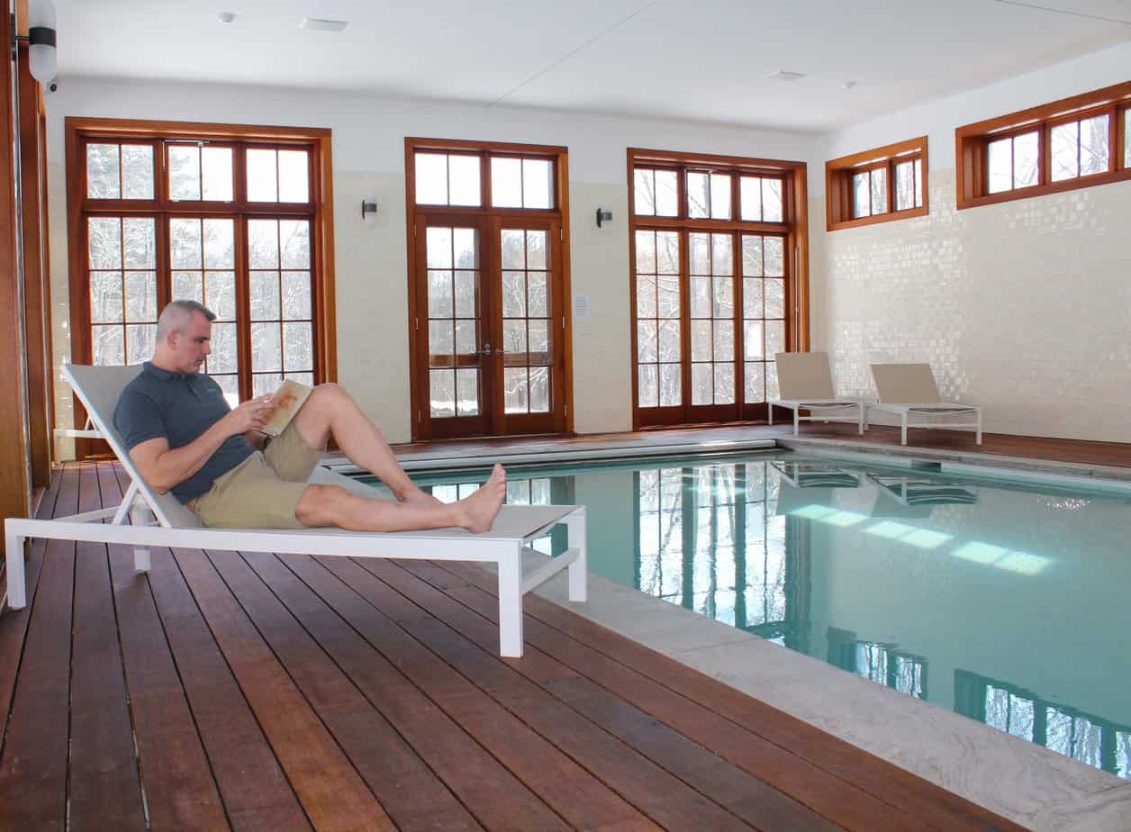 Man in recovery sitting and reading besides the indoor pool at Mountainside's sober living house