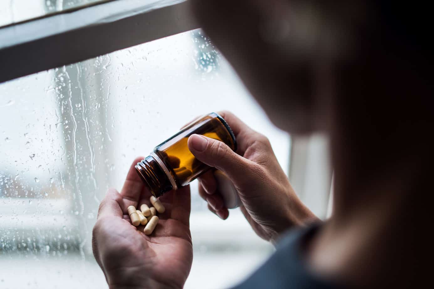woman pouring many pills from a bottle into her palm