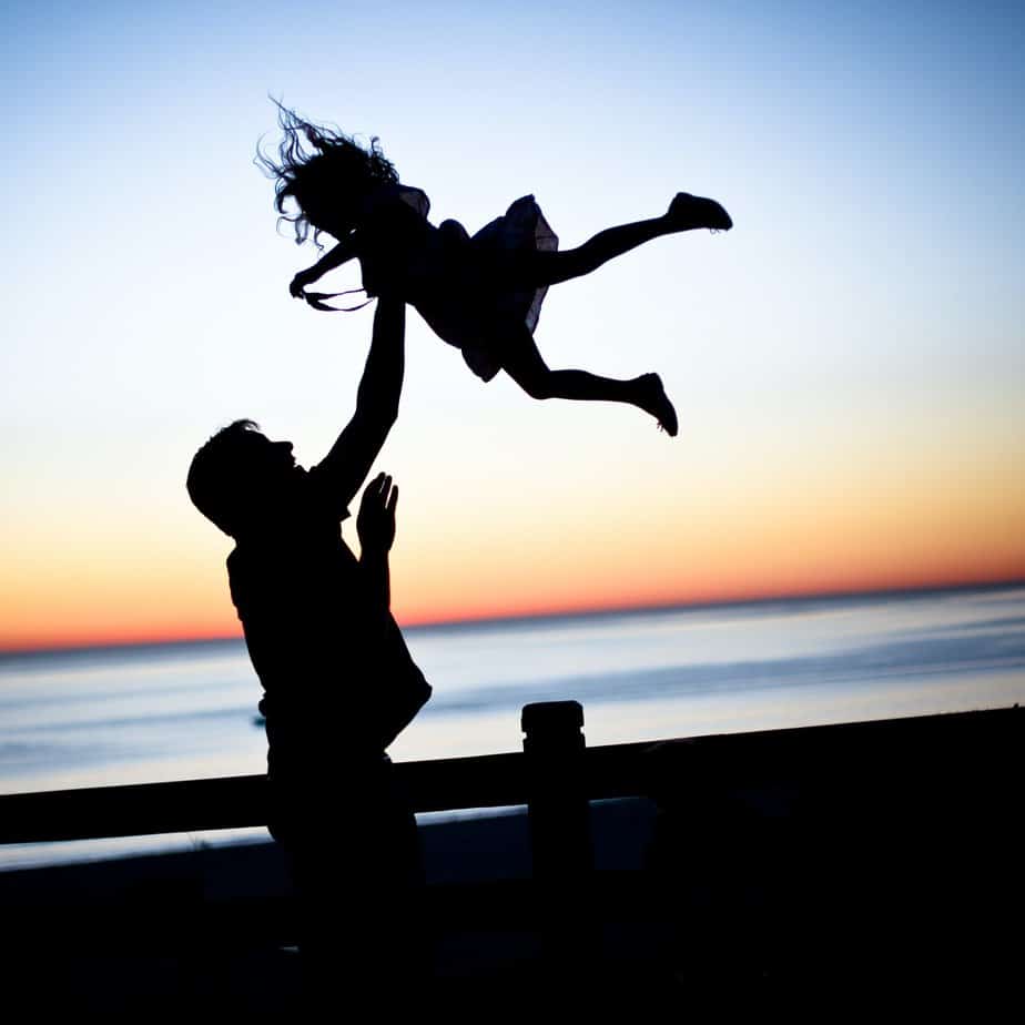 Man tossing daughter playfully at beach