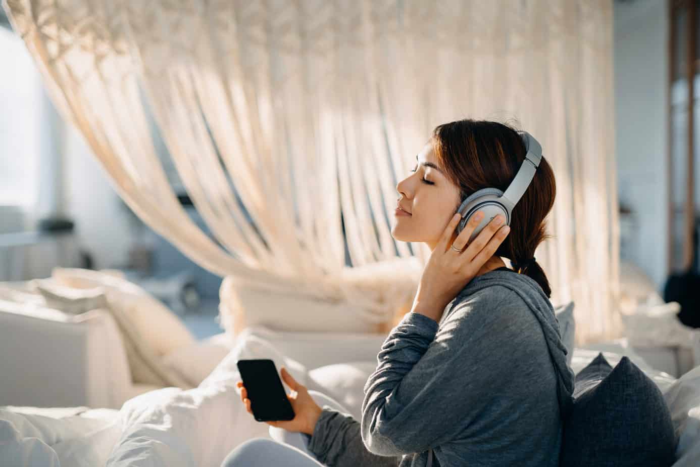 content woman listening to music on bed in bedroom