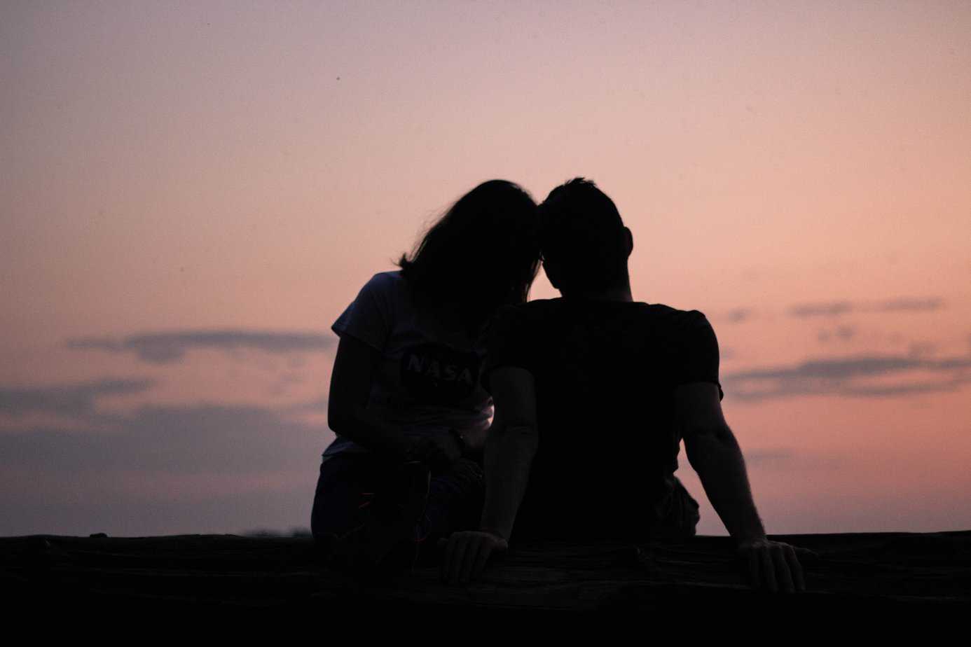 silhouette of couple embracing while watching sunset