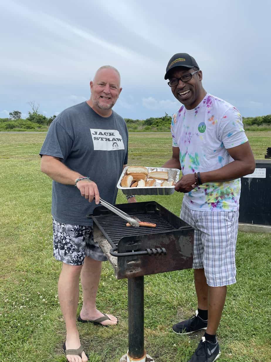 2 men grilling hot dogs outside at Mountainside Treatment Center Alumni Sober Beach BBQ 2022