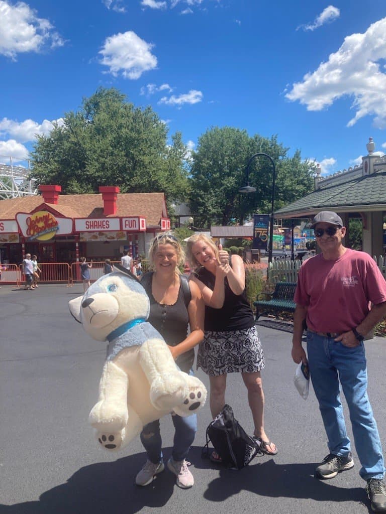 2 woman and man smiling with large stuffed animal at Mountainside Treatment Center Alumni Lake Compounce Event 2022