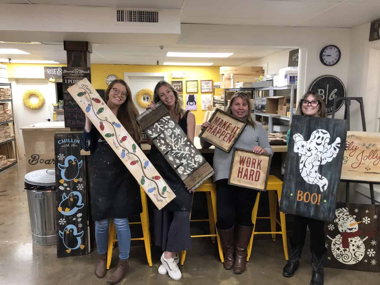 Group photo of women smiling holding painted wooden board art at Mountainside Treatment Center Extended Care Board & Brush Event October 2022