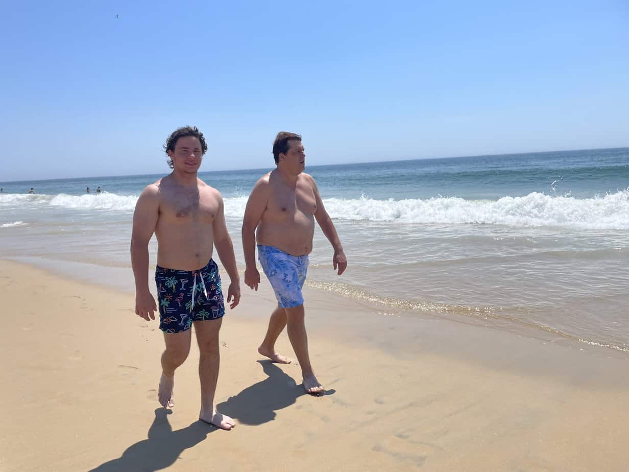 Men in bathing suits walking on sand by ocean at Mountainside Treatment Center Extended Care Watch Hill Beach Event July 2021