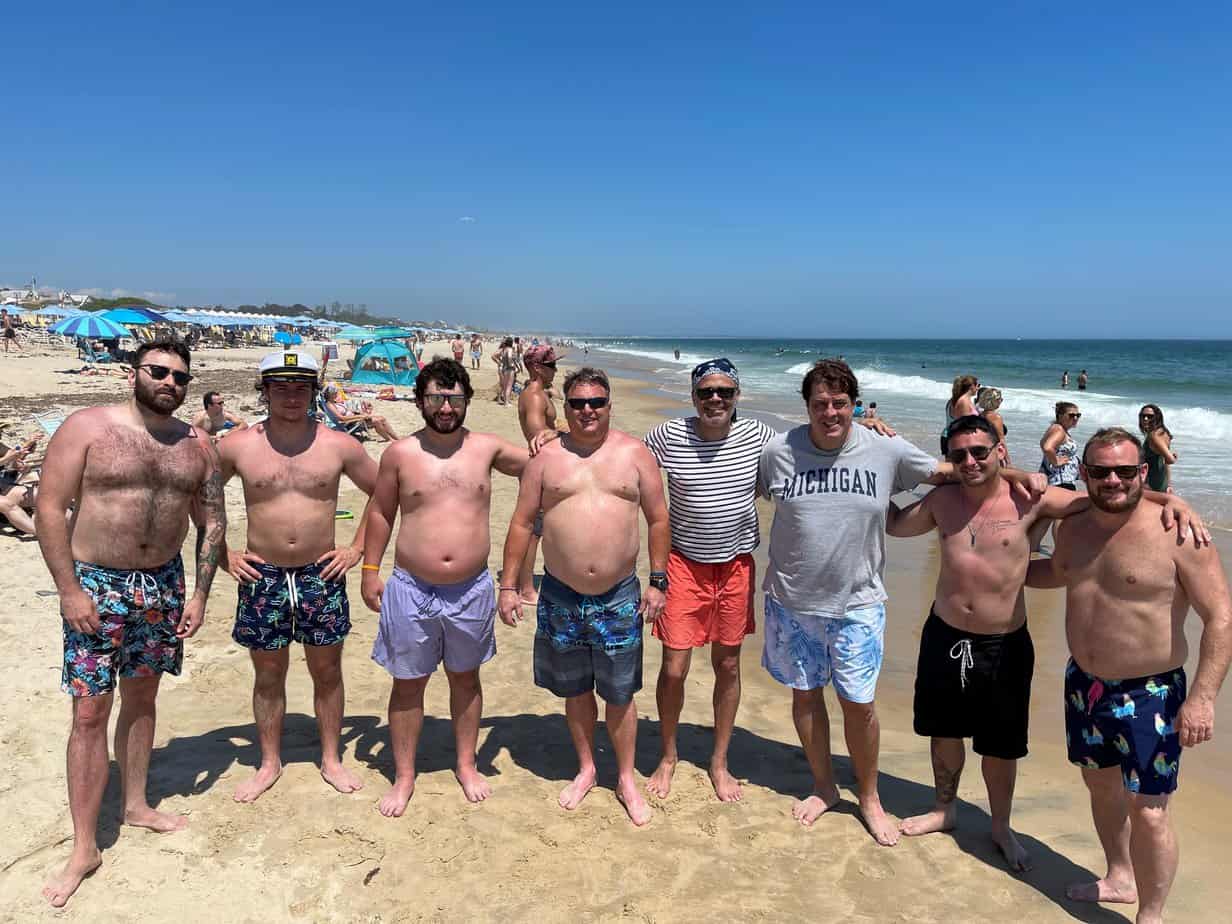 Group photo of men smiling in sand at Mountainside Treatment Center Extended Care Watch Hill Beach Event July 2021