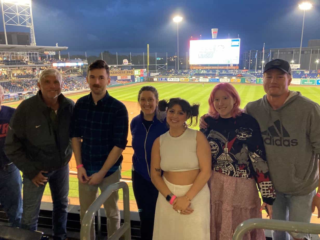 group of people standing in baseball stadium smiling