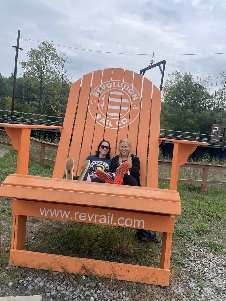 Two women smiling on oversized beach chair at Mountainside Treatment Center Extended Care Revolution Rail Company Event Summer 2022