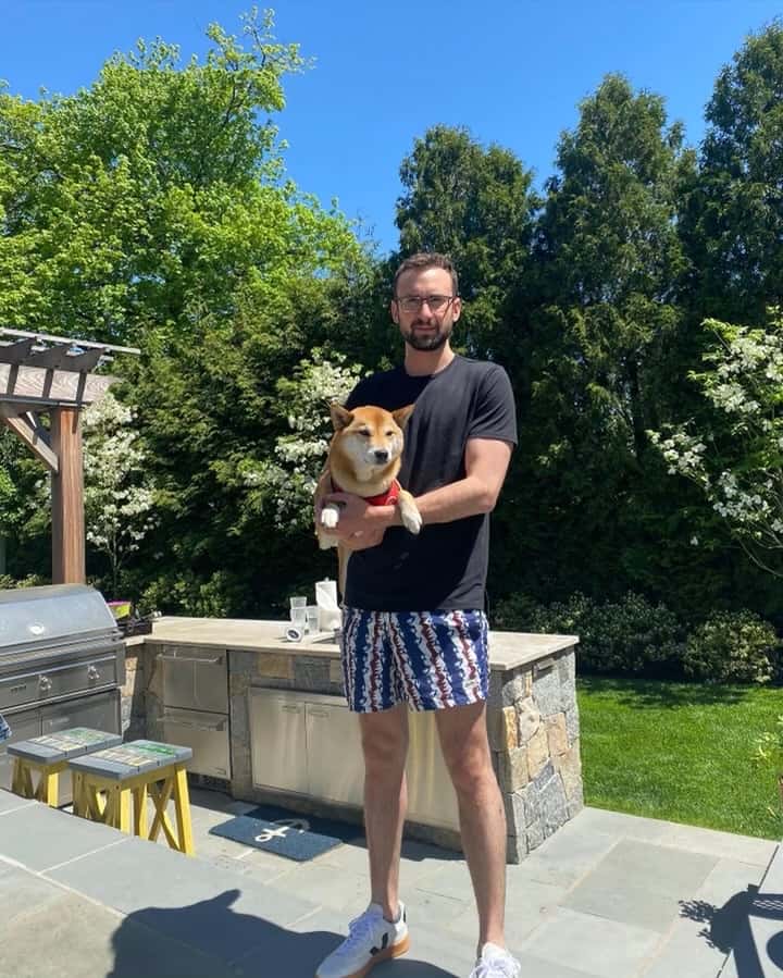 man holding dog on porch in lush backyard