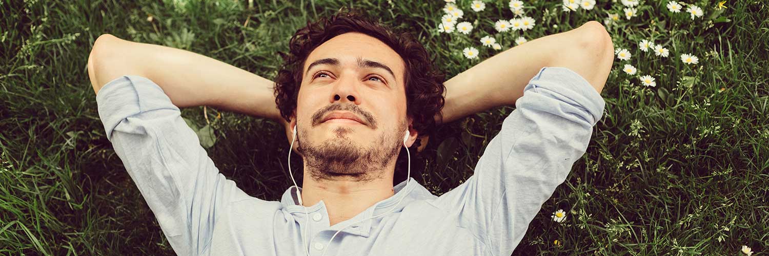 man relaxing in nature listening to music