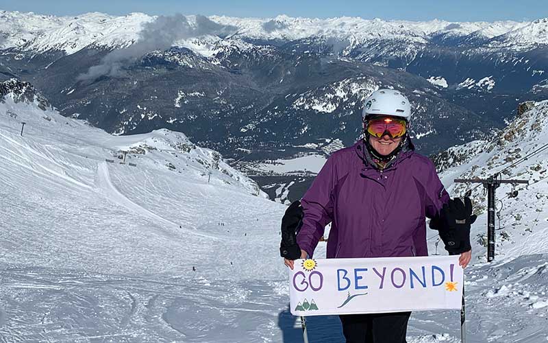 woman on top of mountain holding inspirational banner