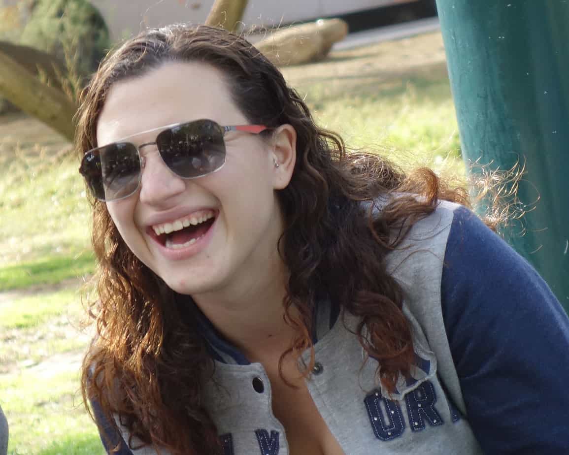 woman in sunglasses grinning outdoors