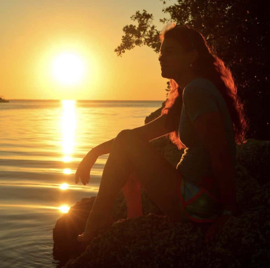 woman gazes out over lake at sunset