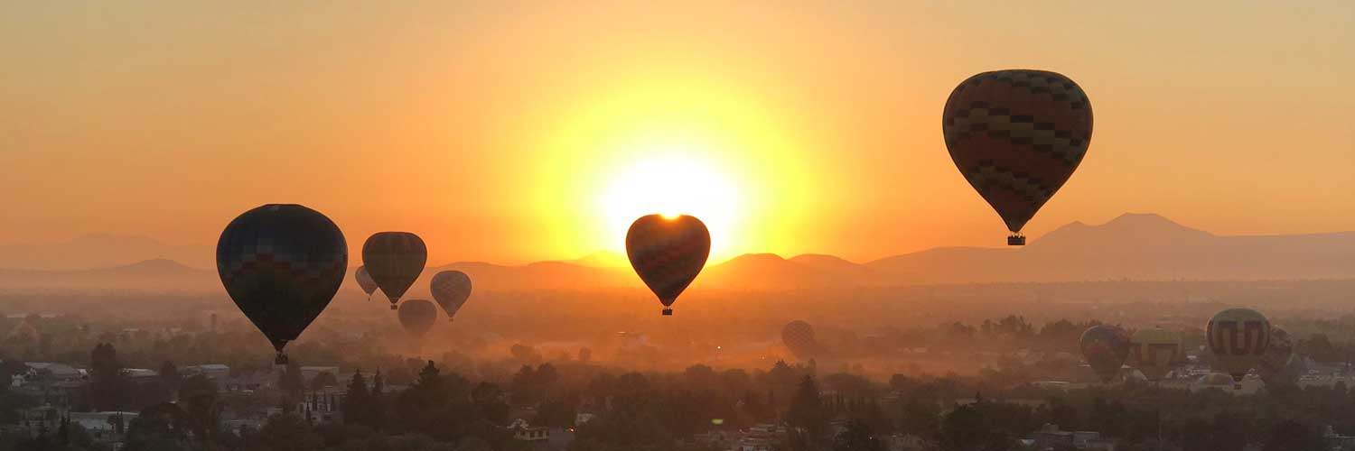 hot air balloons over forest at sunrise