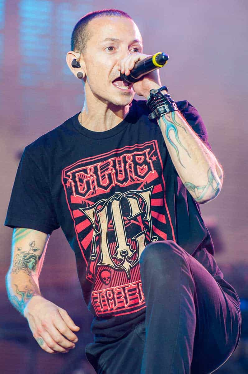 tattooed man in colorful black shirt performs on stage
