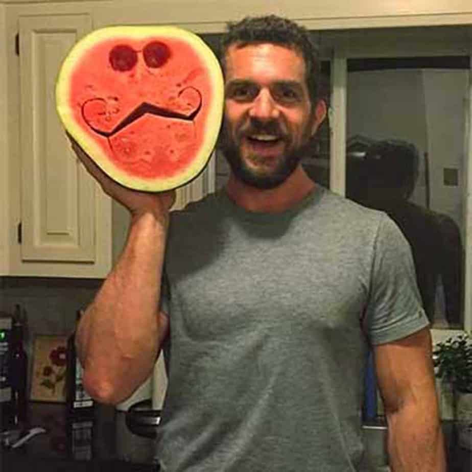smiling bearded man holding carved watermelon