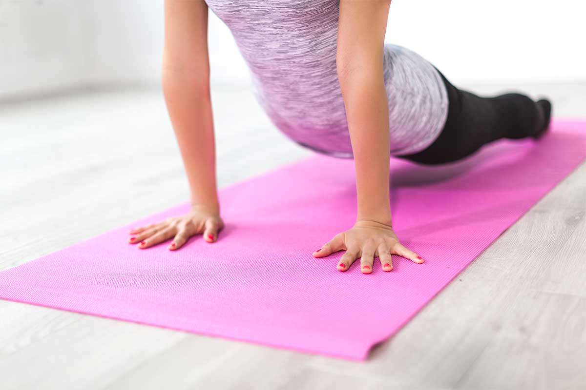 woman wearing athletic gear doing yoga on a pink mat