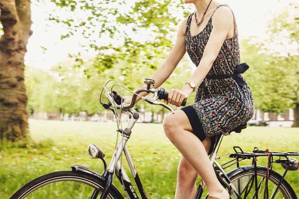woman riding bike through green open park