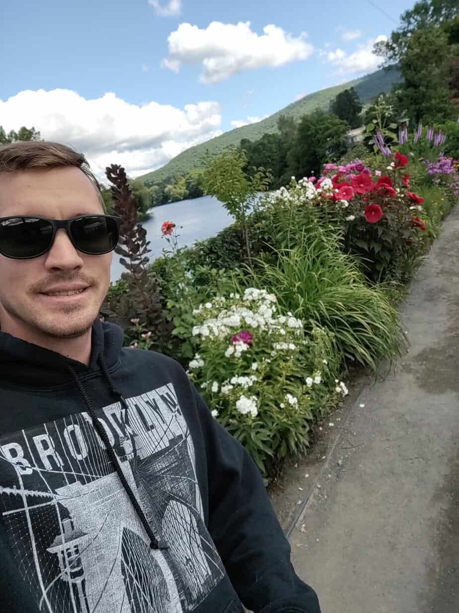man in sunglasses standing in flower garden