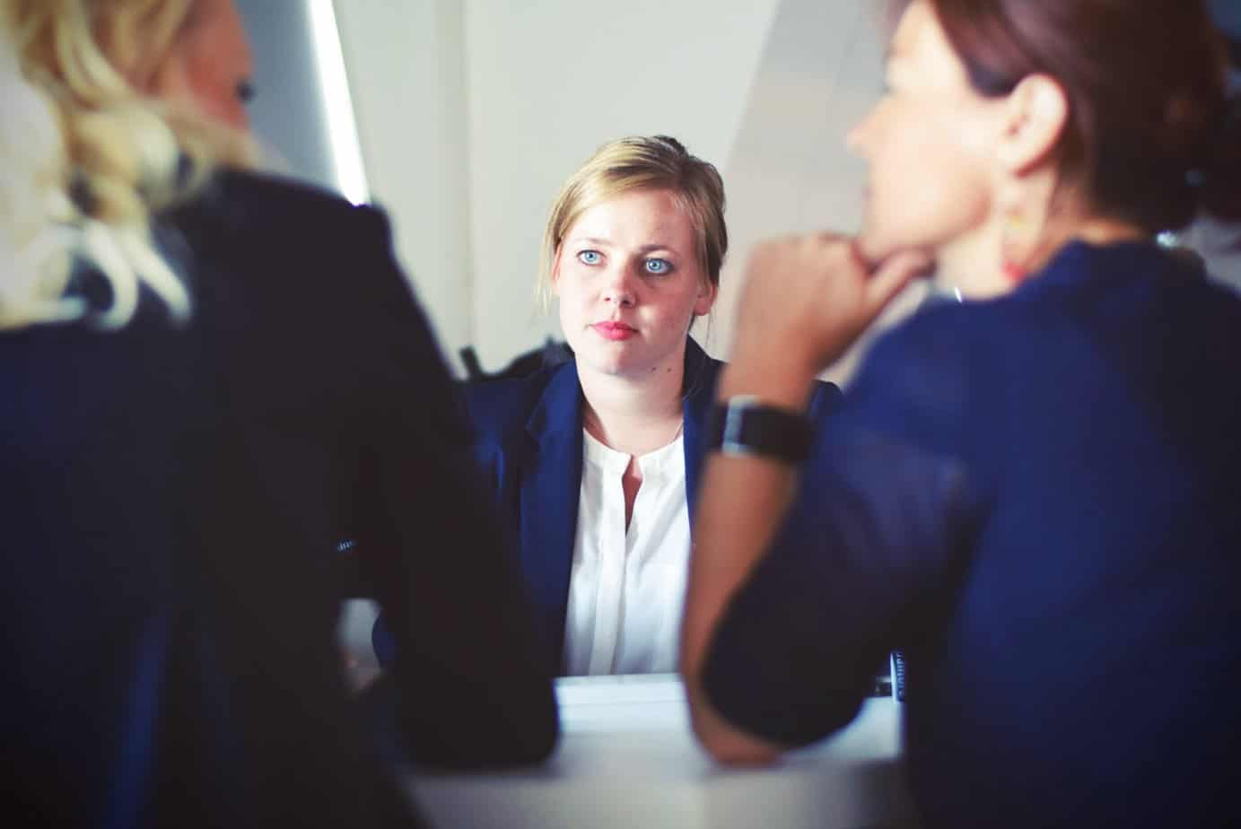 woman looking stressed in business meeting with other woman at table
