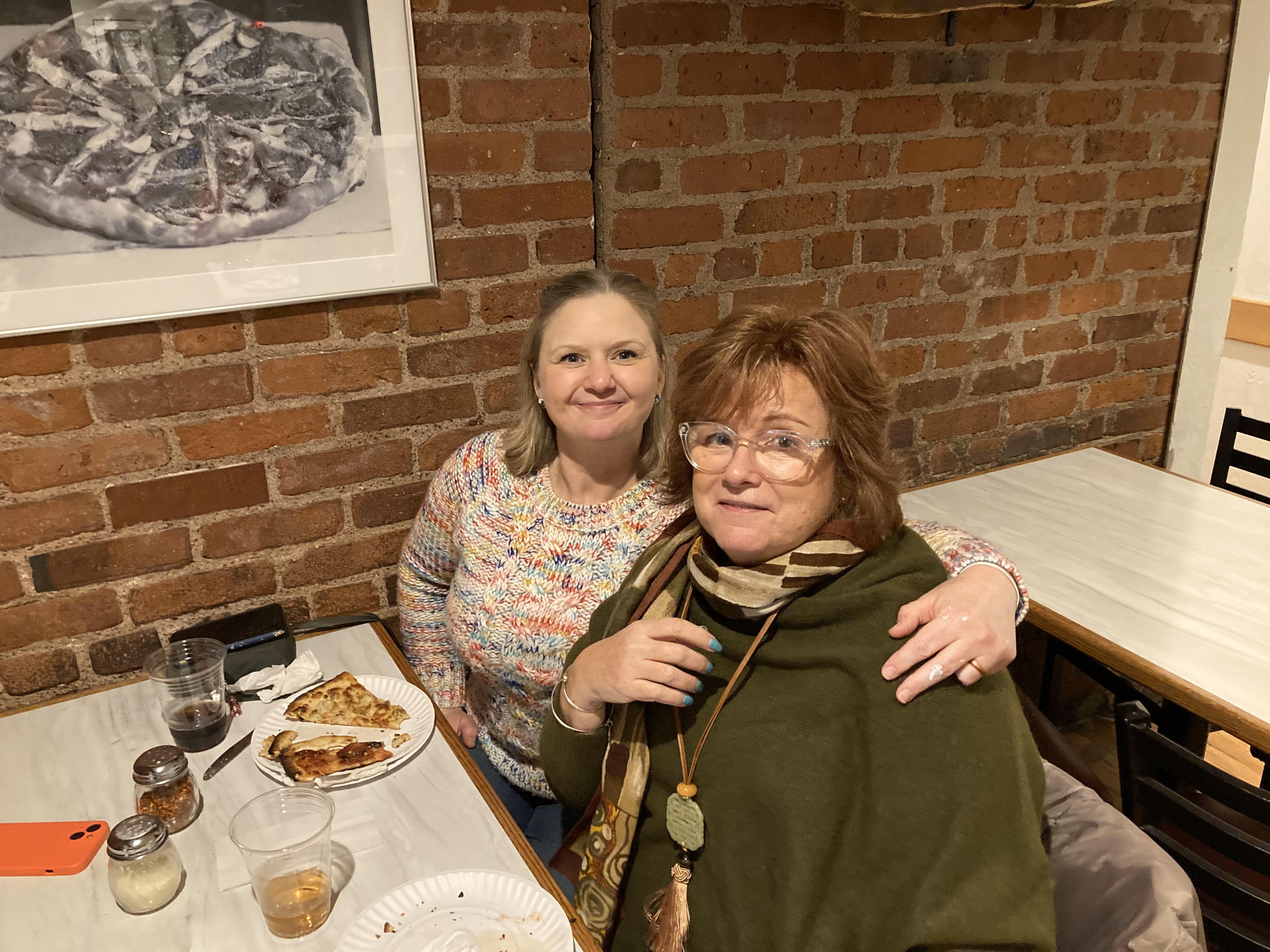Two women smiling around table at Mountainside Treatment Center Alumni Pepe's Pizza Event in Connecticut 2023