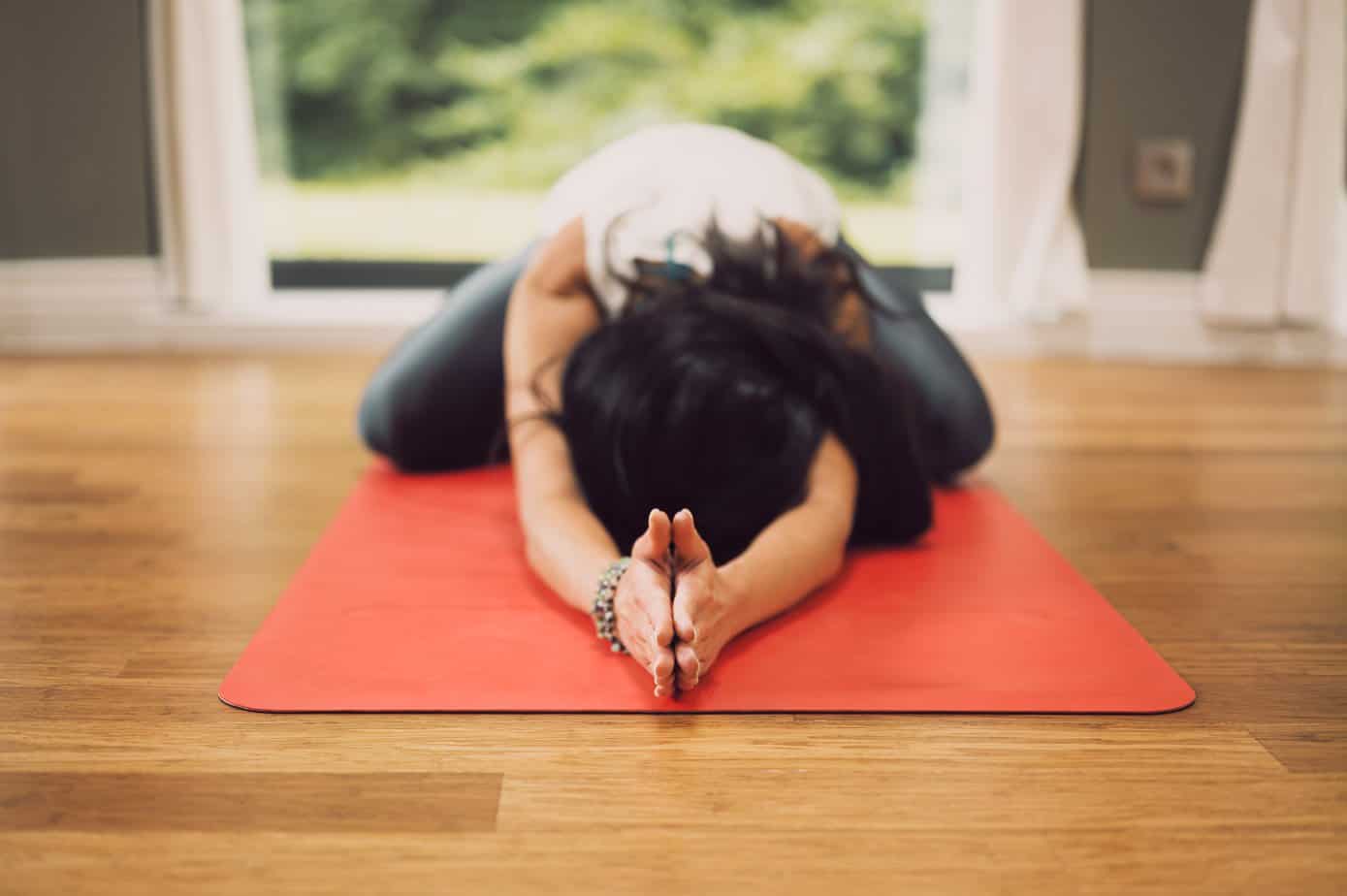 woman laying on red mat practicing yoga poses