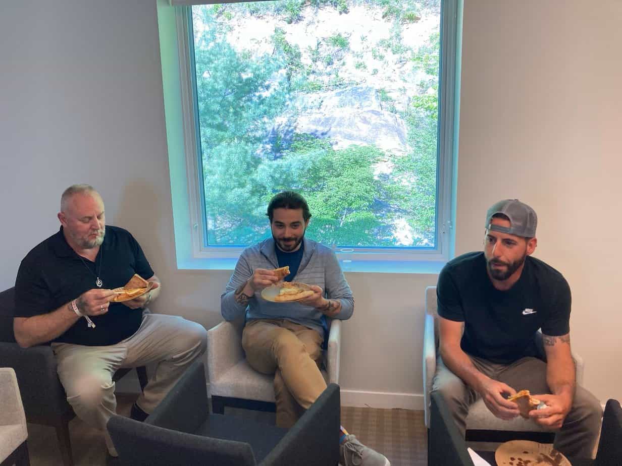 Three men eating pizza at Alumni 2023 Pizza Social at Mountainside Canaan